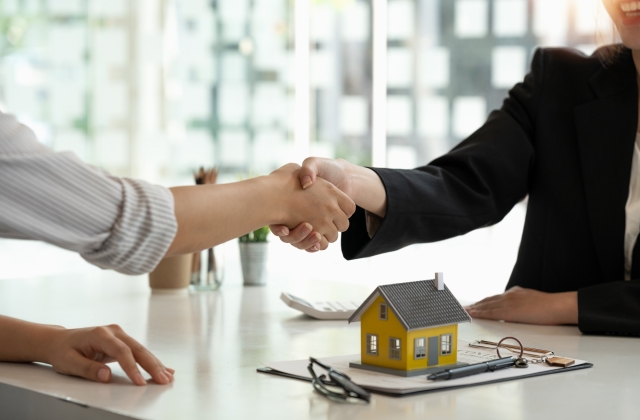 Shaking hands over a small model home