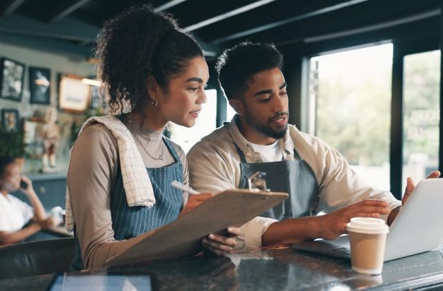 Two people working on laptop at a coffee shop
